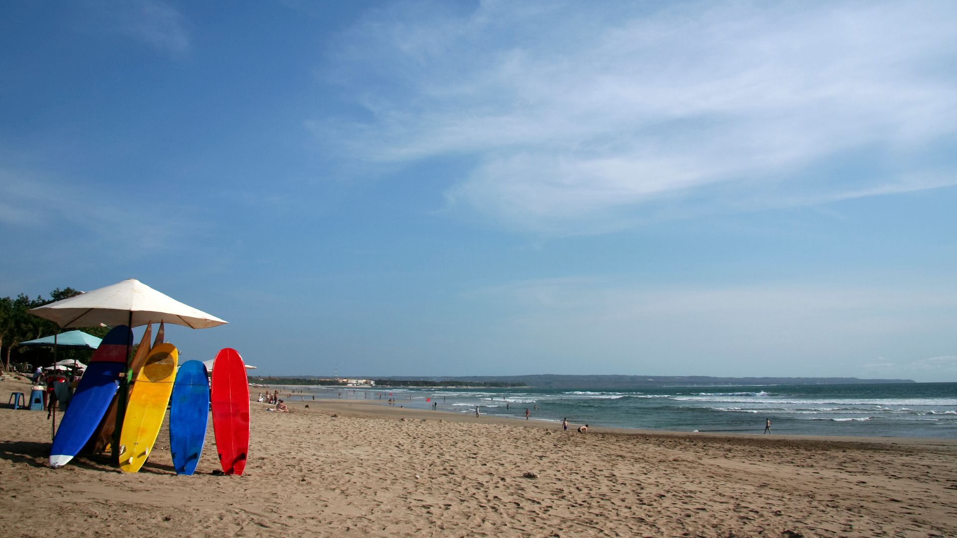 Colorful surfboards lined up under a beach umbrella in Bali, Indonesia