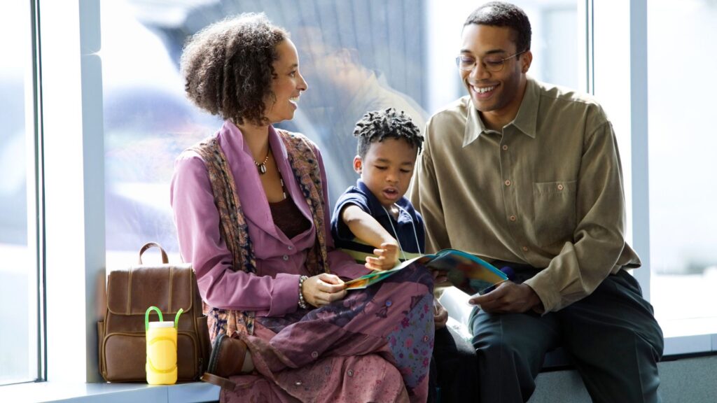 Family relaxing together at an airport gate, reading a book while waiting for their flight 
