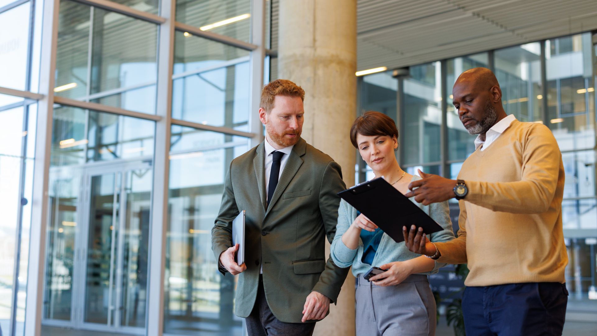 Three colleagues reviewing an international medical insurance plan together outside a modern office building
